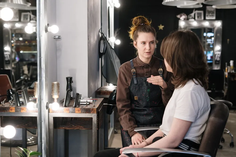 Hair stylist consulting with a client in a salon chair.